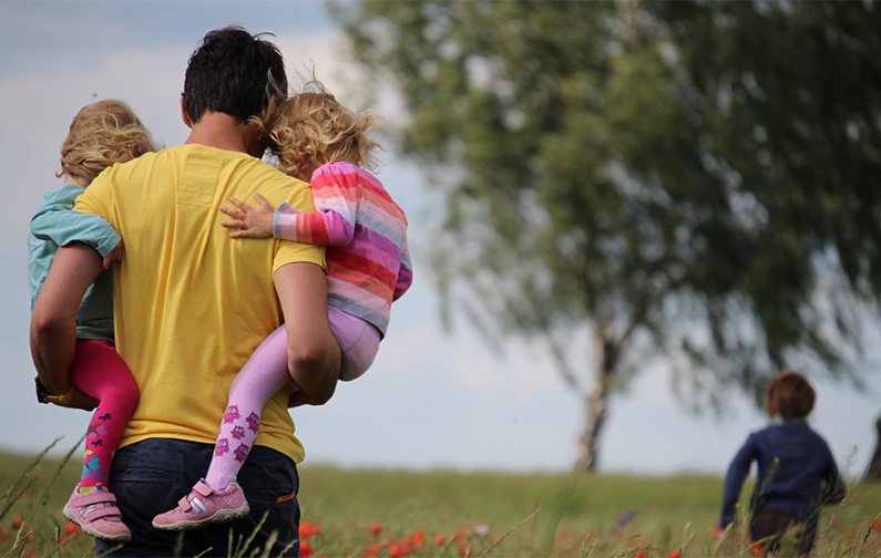 Man with His Children This is an image of a man spending time with his children in a meadow.