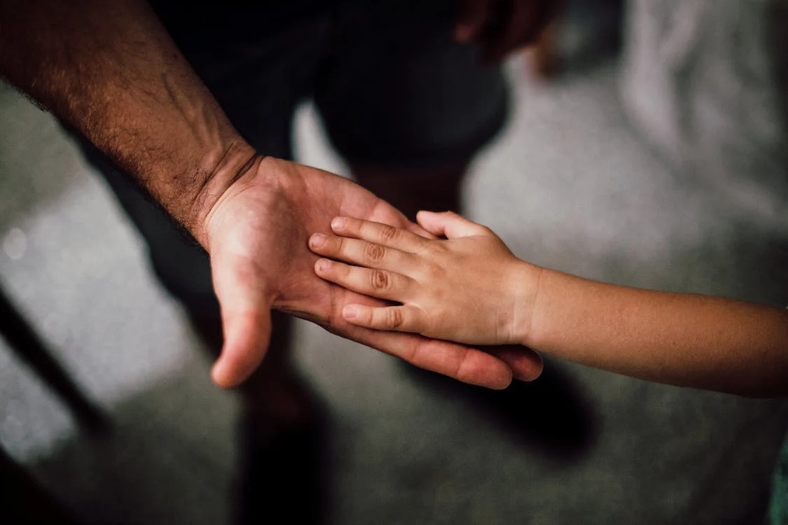 This is an image of a parent reaching out for their child's hand.
