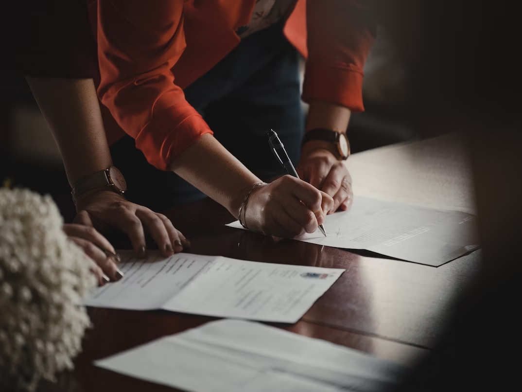 This is an image of two people signing paperwork.