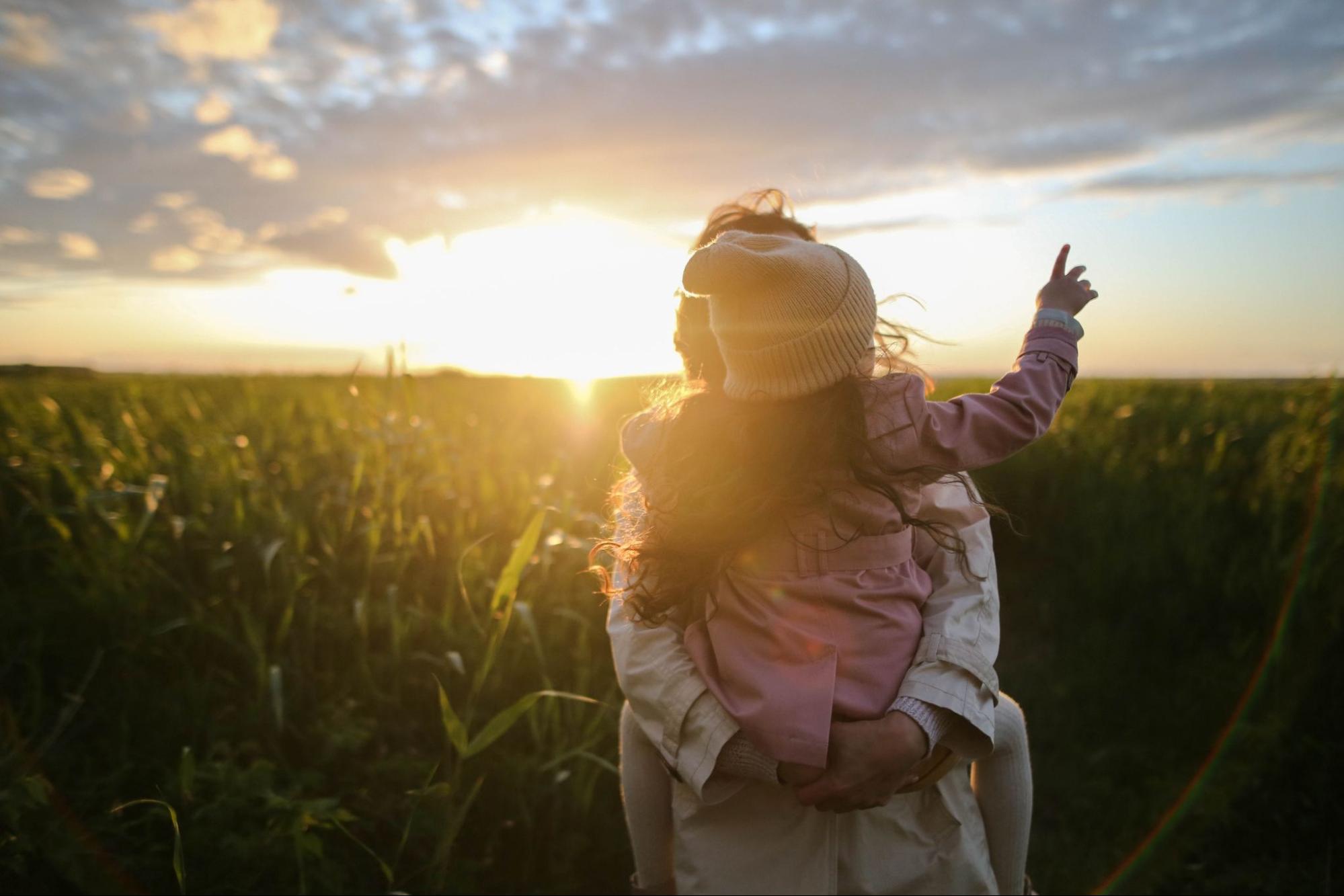 Parent-Child Bonding This is an image of a parent and child spending time together in a field at sunset.