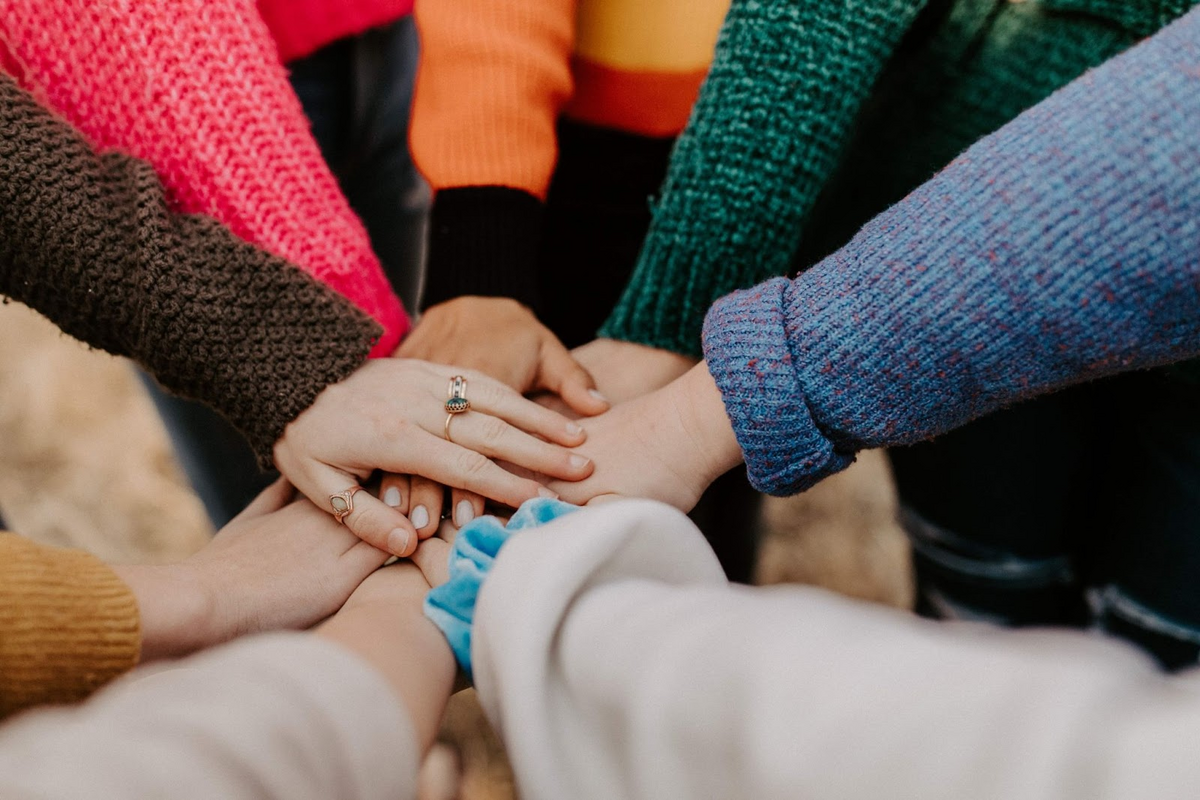 This is an image of several hands placed one over the other in a display of support.