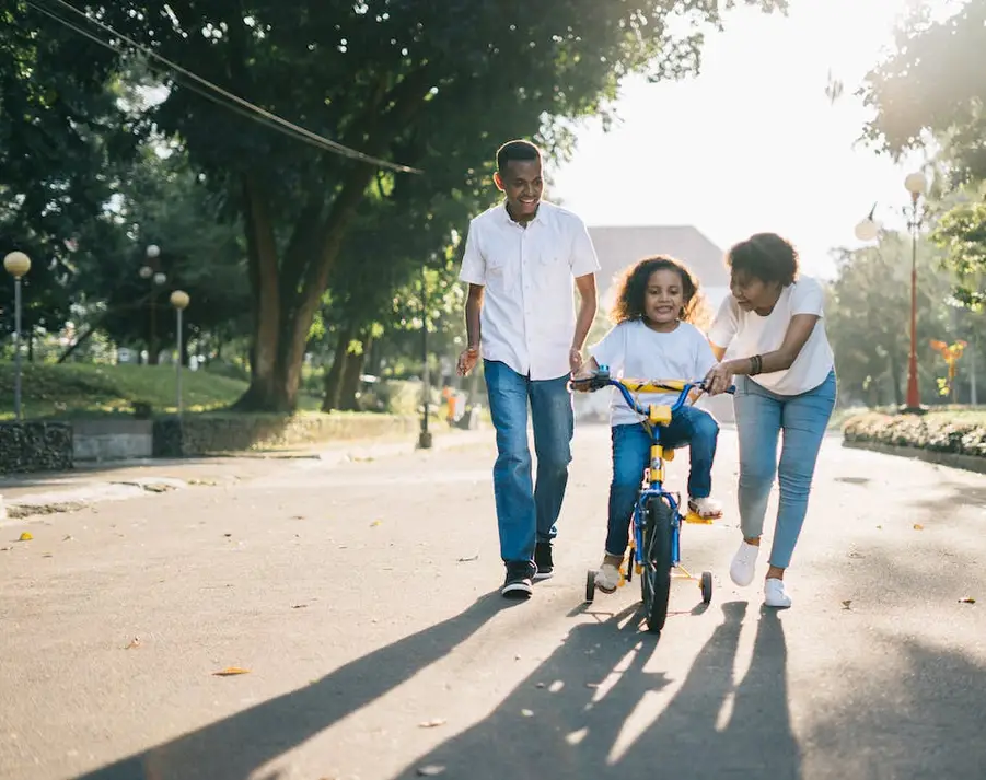 Positive Co-parenting This is an image of two parents helping their child learn how to ride a bike.
