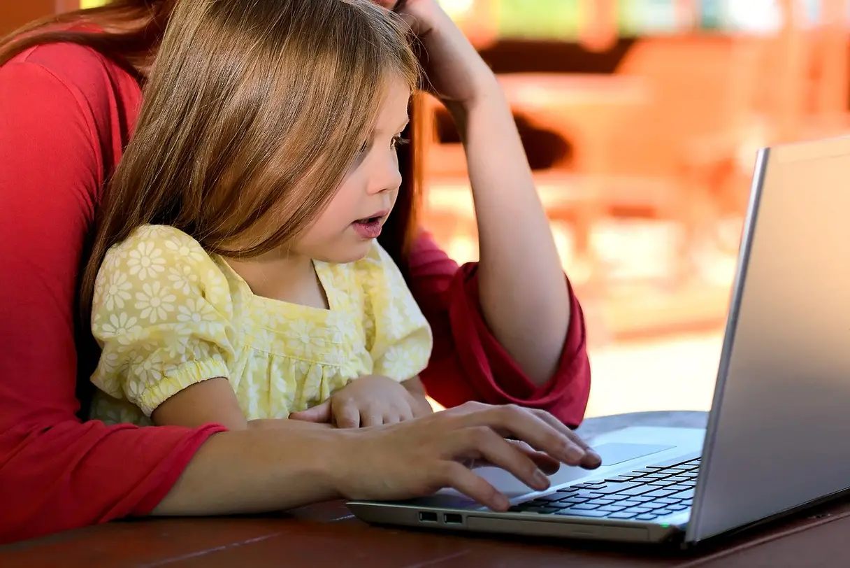 This is an image of a mother with her daughter on a laptop.