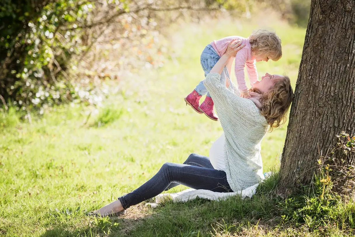 This is an image of a mother lifting her child into the air.