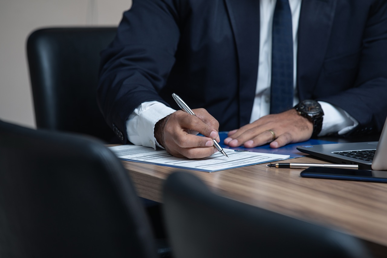 Picture of man wearing a suit, tie, and jacket filling out a form
