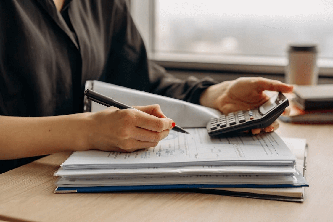 Financial Documents Person with a calculator and a pen writing on paper